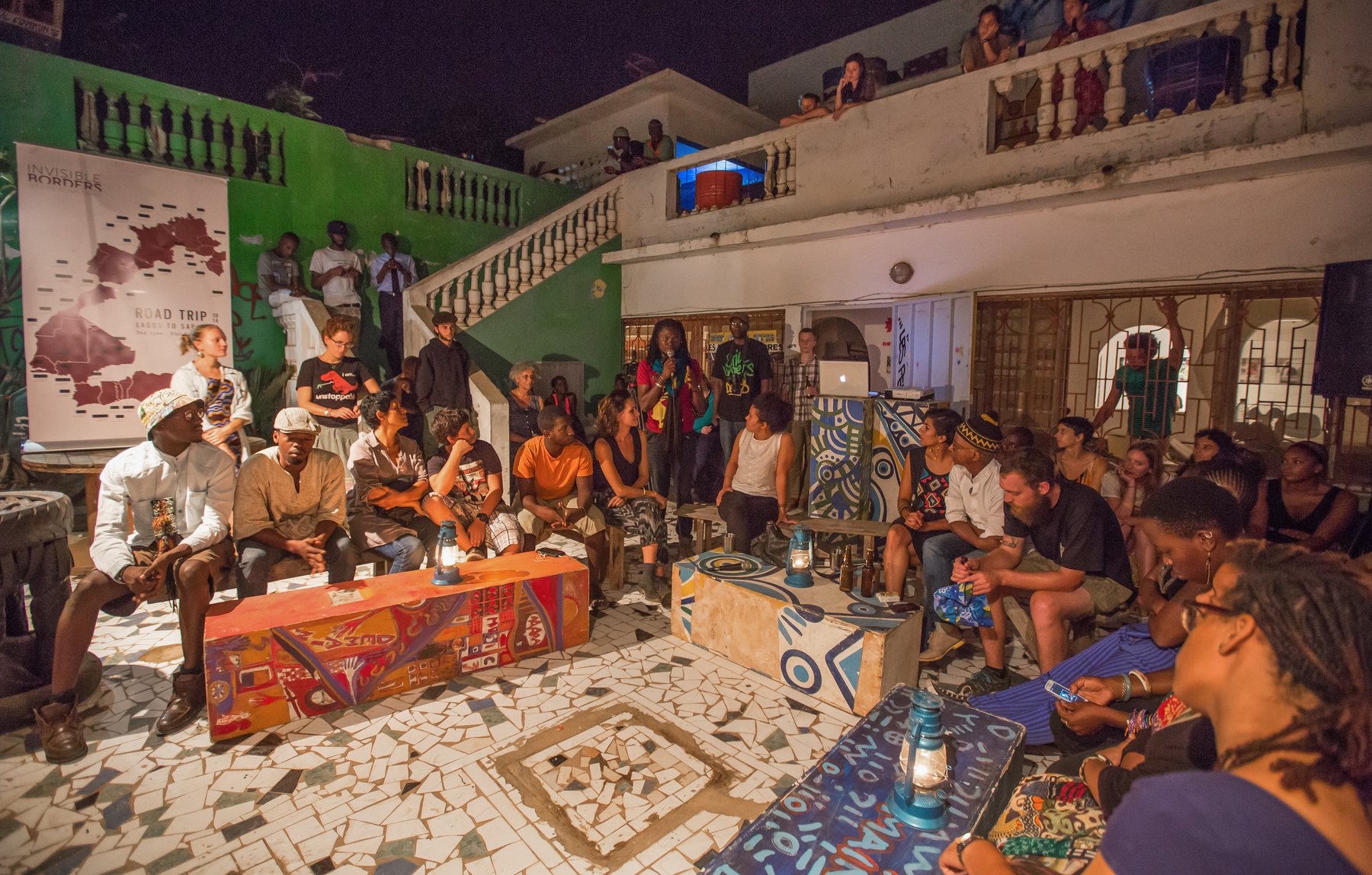 A gathering seated together in a green-walled courtyard in Dakar