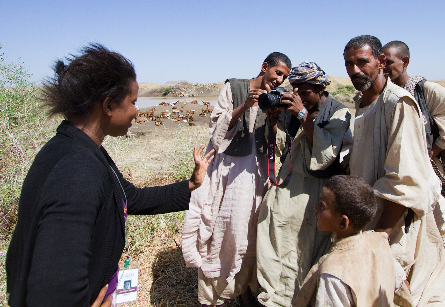 A woman photographing, surrounded by a group of nomads in Sudan